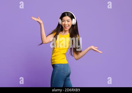 Fröhliche Asiatische Frau Hören Musik In Kopfhörer Und Tanzen Mit Hände Verteilen Stockfoto