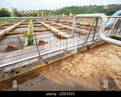 Rohrleitung und Brücke über dem Abwasserbecken. Sedimentationsbehälter in einer Kläranlage Stockfoto