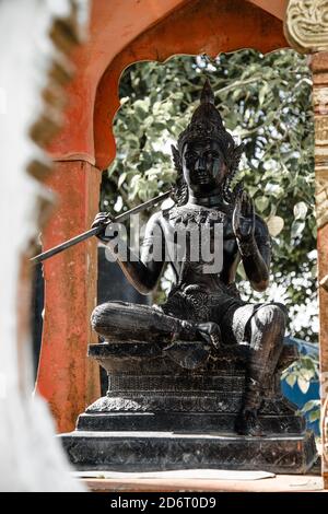 Thailand - 2019. Phra Phutta Ming Mongkol Akenakiri. Schwarze Buddha-Statue auf verschwommenem Laubhintergrund auf Altar. Stockfoto