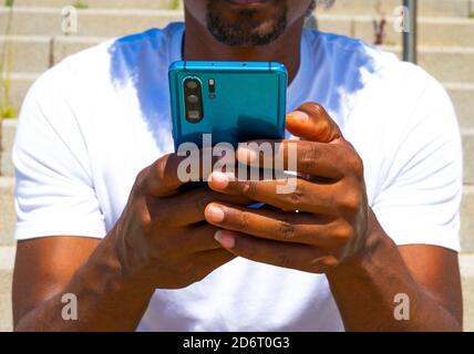 Nahaufnahme eines schwarzen Mannes mit einem blauen Handy. Blaues mobiles Konzept. Stockfoto