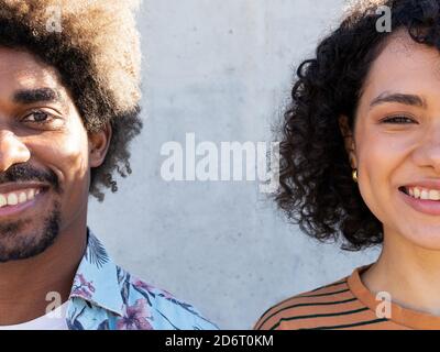 Halbgesicht von fröhlichem jungen schwarzen Mann und Frau mit Afro-Frisur, die auf der Straße stehen und die Kamera an sonnigen Tagen betrachten Stockfoto