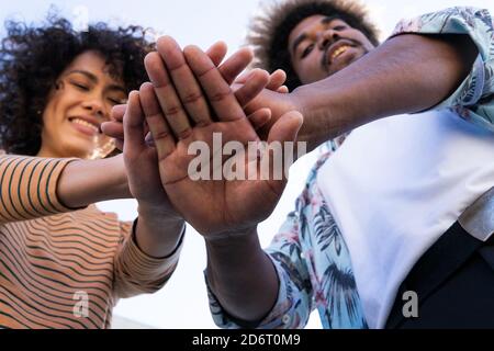 Von unten positive junge afroamerikanische männlich und weiblich Hände zusammenlegen und lächeln, während Sie Spaß an der Sonne haben Tag Stockfoto