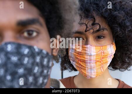 Schneiden Sie nicht erkennbare ethnische junge Mann und Frau mit Afro-Haar in Schutzmasken Blick auf die Kamera Stockfoto