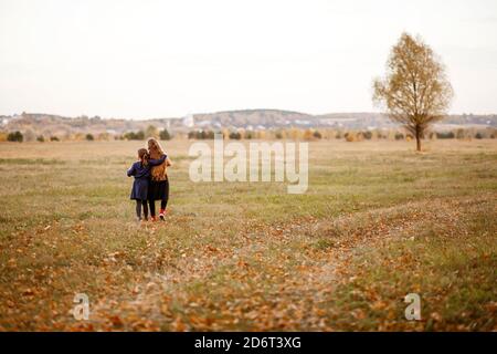 Zwei Mädchen im Teenageralter gehen im warmen Herbst an einer Waldstraße entlang. Stockfoto