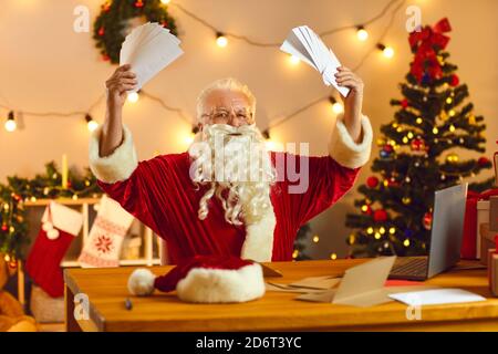 Erstaunt hält der ältere Weihnachtsmann viele Briefe von Kindern mit Wunschlisten in den Händen. Stockfoto