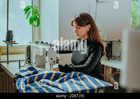 Schneiderin, die am Arbeitsplatz an der Nähmaschine arbeitet Stockfoto