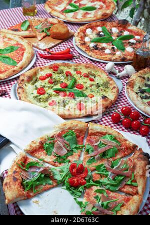 Von oben appetitlich traditionelle italienische Pizzen mit verschiedenen Füllungen Serviert auf dem Tisch mit karierter Tischdecke während der Party Stockfoto