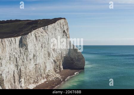 Malerische Landschaft von riesigen Kreidefelsen mit grünem Gras bedeckt Das Hotel liegt am blauen Meer an sonnigen Tag in Seven Sisters Stockfoto