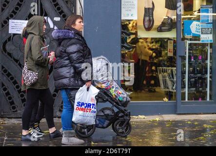 Dundee, Tayside, Schottland, Großbritannien. Oktober 2020. UK Wetter: Trüber und trüber Tag mit leichtem Regen über Nord-Ost Schottland, Höchsttemperaturen 12 Grad Eine Frau, die einen Kinderwagen mit Kind schiebt, während sie an einem nassen Nieseltag im Stadtzentrum von Dundee während der Covid-19-Sperre einkaufen. Kredit: Dundee Photographics/Alamy Live Nachrichten Stockfoto