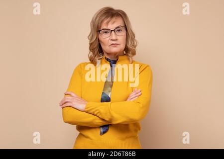 Ernst kaukasische Frau in einer Brille stehen mit gefalteten Händen und Blick auf die Kamera Stockfoto