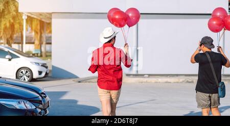 Rückansicht des homosexuellen Mann im roten Hemd mit roten Ballons vom Parkplatz der Partei am Nachmittag zu verbinden. Stockfoto