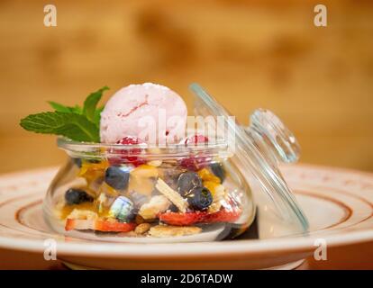 Nahaufnahme von köstlichen Kugel Eis in Glas serviert Glas mit verschiedenen Beeren und garniert mit Zweig der Minze Stockfoto