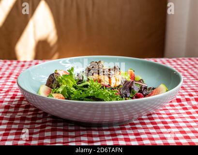 Goat Roller Cheese Salat serviert auf dem Teller mit verschiedenen Früchten Und frisches Grün auf dem Tisch im Café Stockfoto