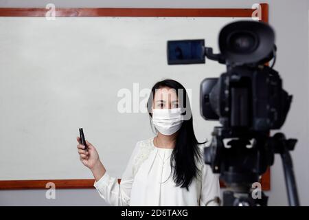 Lehrer mit Atemschutzmaske während der Präsentation von Online-virtuellen Klasse Stockfoto