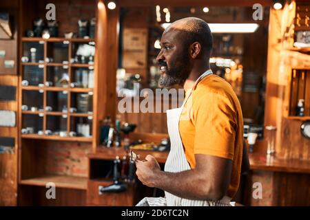 Schöner afroamerikanischer Mann mit Haarschneider im Friseurladen Stockfoto