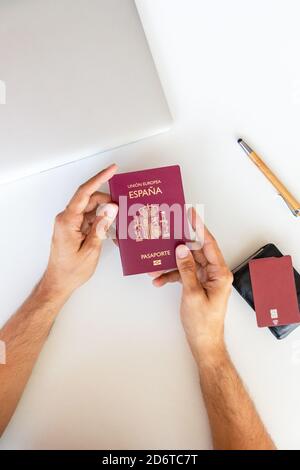 Ansicht von oben auf Ernte männlichen Touristen sitzen am Tisch mit Pass und Laptop während der Vorbereitung auf den Urlaub im Sommer Stockfoto