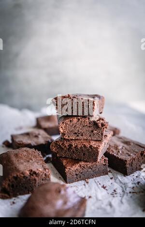 Stapel von leckeren weichen Brownie Stücke auf Pergament in der Nähe glänzend Wand im Haus Stockfoto