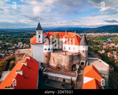 Luftaufnahme der mittelalterlichen Burg auf dem Berg in der kleinen europäischen Stadt im Herbst Saison. Schloss Palanok, Mukachevo, Ukraine Stockfoto