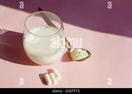 Kollagen oder Proteinpulver in einem Glas auf rosa Hintergrund. Natürliches Sonnenlicht. Wellness-Drink aus nächster Nähe Stockfoto