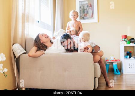 Glückliche Mutter und Vater spielen mit entzückenden Kindern auf dem Sofa Am Wochenende zu Hause Stockfoto