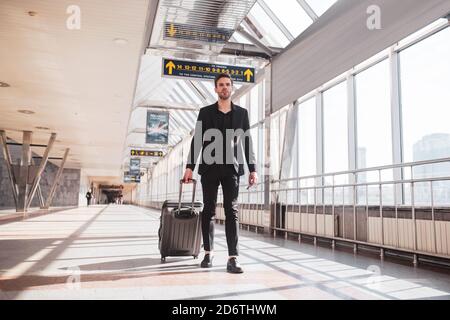 Mann, der seinen Koffer durch den Bahnhof trägt Stockfoto