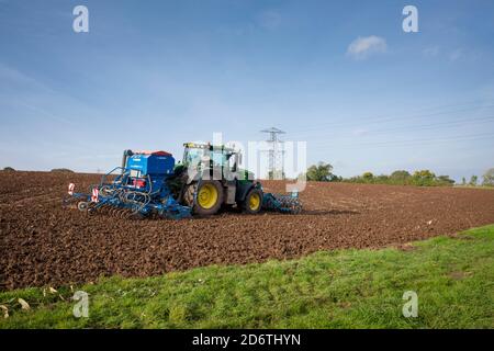 Ein John Deere Traktor 6175R, der mit einer pneumatischen Sämaschine Lemken Solitair 9 Samen auf einem frisch gepflügten Feld aussaat. Wrington, North Somerset, England. Stockfoto