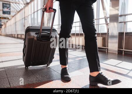 Mann, der seinen Koffer durch den Flughafen trägt Stockfoto