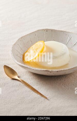 Von oben appetitlich italienische Panna Cotta mit Orangenmarmelade In der Schüssel neben dem Löffel auf dem Tisch Stockfoto