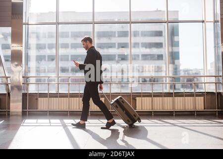 Mann, der mit dem Gepäck durch den Flughafen läuft Stockfoto