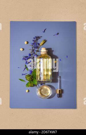 Flasche mit natürlichem kosmetischen Aromaöl und Pipette auf blau Hintergrund in Blumen Stockfoto