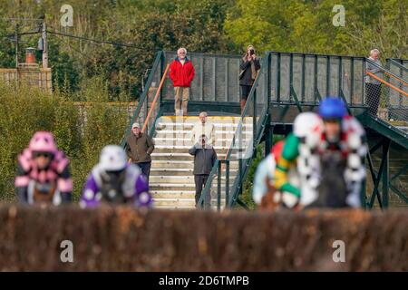 Eine allgemeine Ansicht als Rennfahrer beobachten die William Hill Novices' Limited Handicap Chase von der Plumpton Station Railway Fußgängerbrücke auf der Plumpton Racecourse. Stockfoto