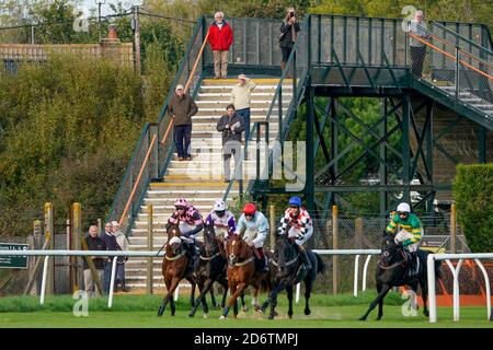 Eine allgemeine Ansicht als Rennfahrer beobachten die William Hill Novices' Limited Handicap Chase von der Plumpton Station Railway Fußgängerbrücke auf der Plumpton Racecourse. Stockfoto