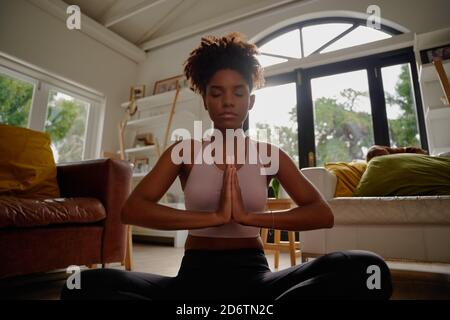 Portrait einer jungen afrikanischen Yogistin, die Yoga in Namaste praktiziert Position und geschlossene Augen Stockfoto