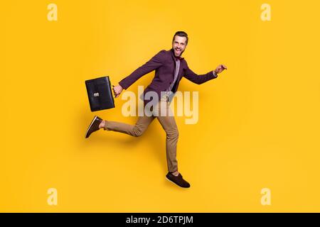 In voller Größe Profil Foto von schönen stilvollen Business-Kerl springen Hoch bis eilig Arbeit Büro halten Aktentasche tragen kariertes Hemd blazer-Hosenschuhe Stockfoto