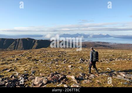 Walker auf Sgurr a Chaorachain mit Blick über die Bealach na Ba the in Richtung Isle of Skye, Applecross, Schottland, Großbritannien Stockfoto