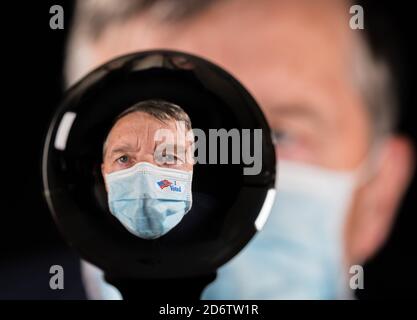 Senior Mann trägt Gesichtsmaske und ich stimmte Aufkleber für Coronavirus und reflektiert in Glück sagen Glaskugel. Konzept, um Wähler in Wahlen zu zeigen Stockfoto