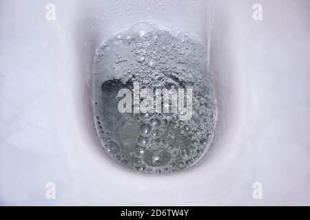 Spülen Sie das Wasser in der Schüssel einer weißen Toilette Stockfoto