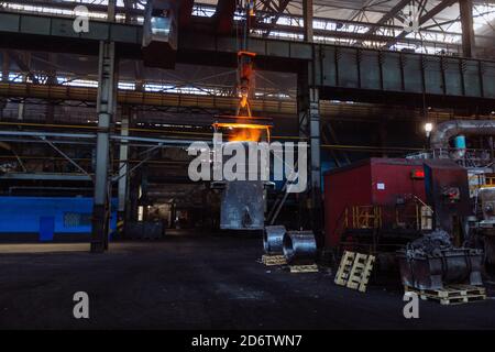 Eisenguss und die Gießerei. Deckenkran mit Schöpfkelle aus geschmolzenem Metall in der metallurgischen Fabrik Stockfoto