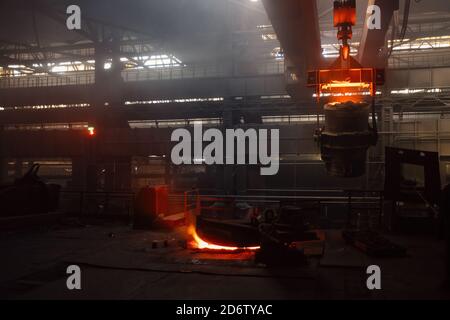 Eisenguss und die Gießerei. Deckenkran mit Schöpfkelle aus geschmolzenem Metall in der metallurgischen Fabrik Stockfoto