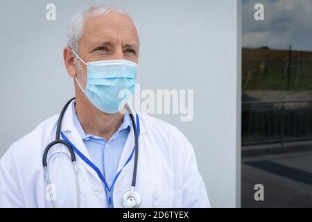 Leitender Arzt mit Gesichtsmaske vor grauem Hintergrund Stockfoto