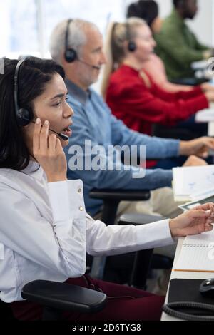 Geschäftsfrau mit Headset bei der Arbeit im Büro Stockfoto