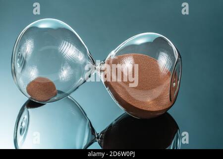 Sanduhr mit braunem Quarzsand auf der Spiegelfläche Stockfoto