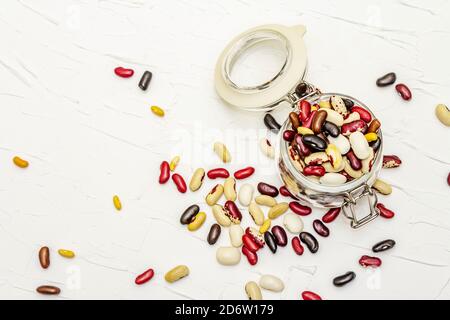 Verschiedene Arten von Bohnen in Glas. Mix aus verschiedenen trockenen Hülsenfrüchten auf weißem Kitt Hintergrund, Draufsicht Stockfoto