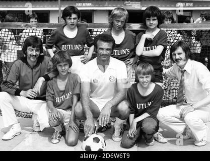 Butlins Filey, North Yorkshire, England, Großbritannien. 1975-1977 Archivbilder von Urlaubern & Rotkittern bei Butlins Filey. LEED Utd-Spieler Paul Reaney mit jungen Fußballern und rotem Mantel Stockfoto