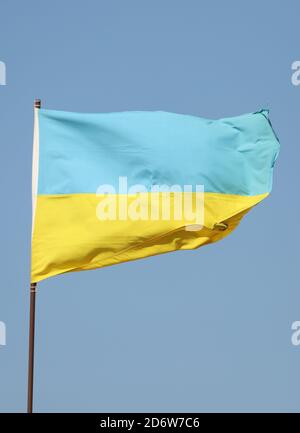 Ukrainische Flagge auf Fahnenmast auf blauem Himmel Hintergrund fliegen Stockfoto