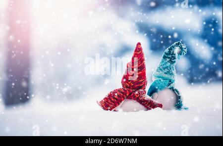 Kleine Schneemänner auf weichem Schnee auf blauem Hintergrund bei Schneefall Stockfoto