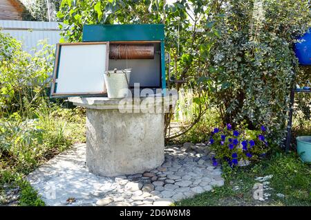 Alte Ziehbrunnen im europäischen Dorf. Retro Steinwasserbrunnen in ländlicher Umgebung Stockfoto