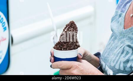 Ich habe gerade eine kleine Tasse Eis vom Eismann mit Schokoladenstreuseln gekauft. Stockfoto