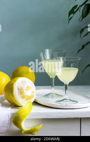 Italienischer Likör Limoncello in Kristallgläsern und reife Zitronen auf einem Holztisch. Stockfoto