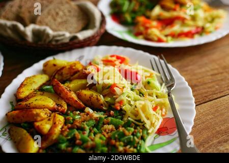 Einfache Lebensmittel zu Hause bestellen. Eine Portion grüne Bohnen, Bratkartoffeln und Salat auf einem Teller. Stockfoto